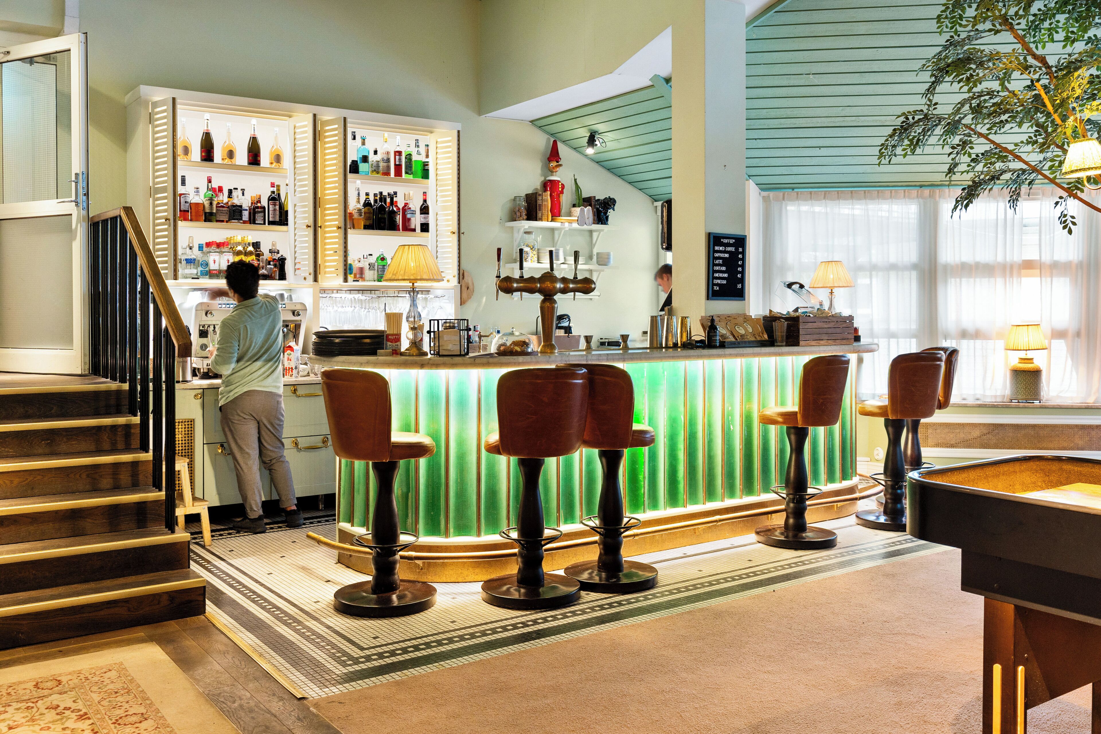 Una zona de bar con taburetes, una barra y una escalera que sube a otro nivel.