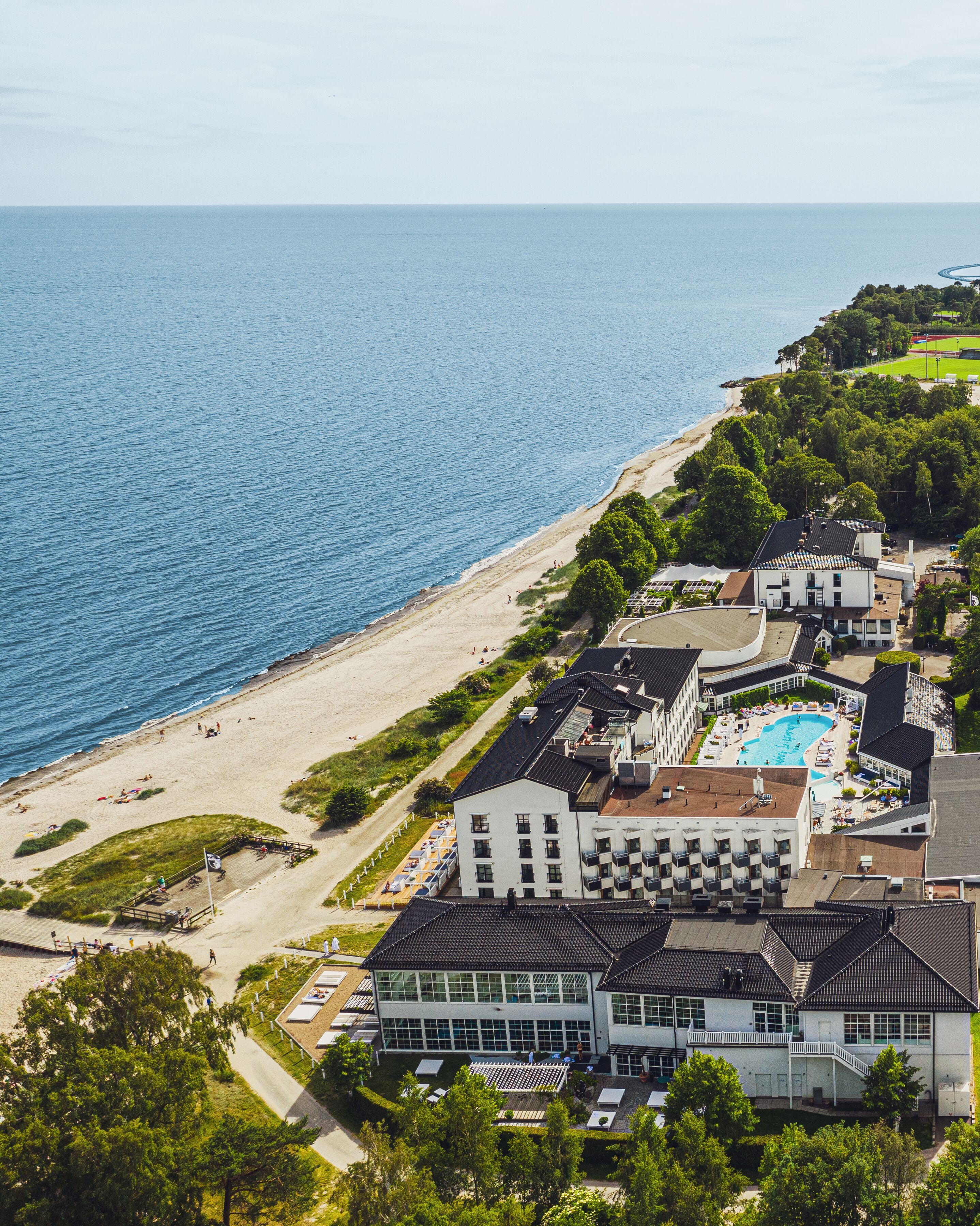A coastal hotel with a swimming pool, beach access, and a view of the sea.