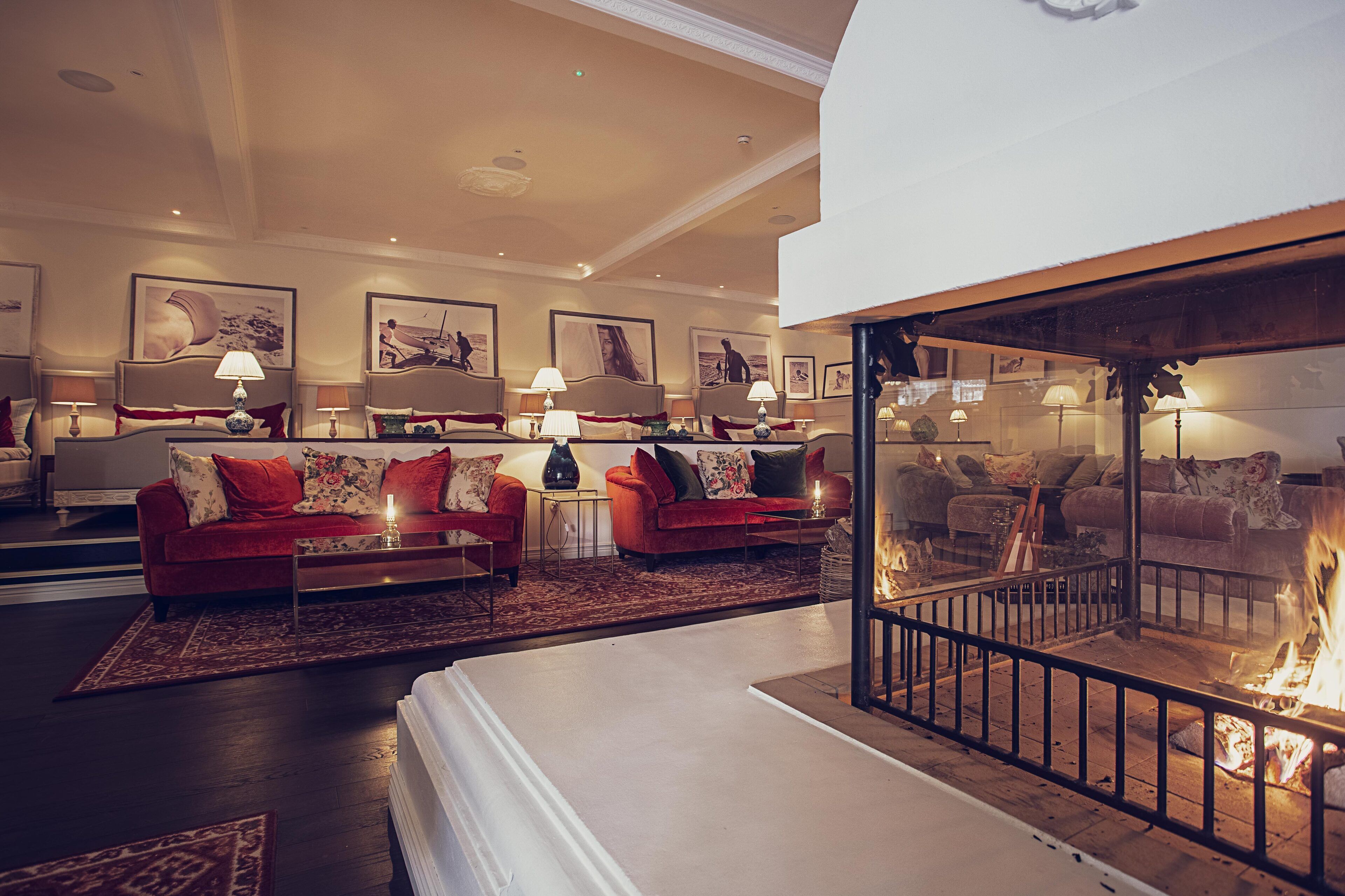 A spacious living room with red sofas, a fireplace, and artwork on the walls.