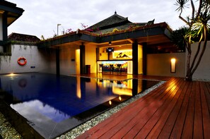 A swimming pool with a wooden deck, a lifebuoy, and a building with a tiled roof. - The Yani Hotel Bali (Denpasar)