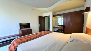 A hotel room with a large bed, a desk, a chair, a television, and a wardrobe. - The Yani Hotel Bali (Denpasar)