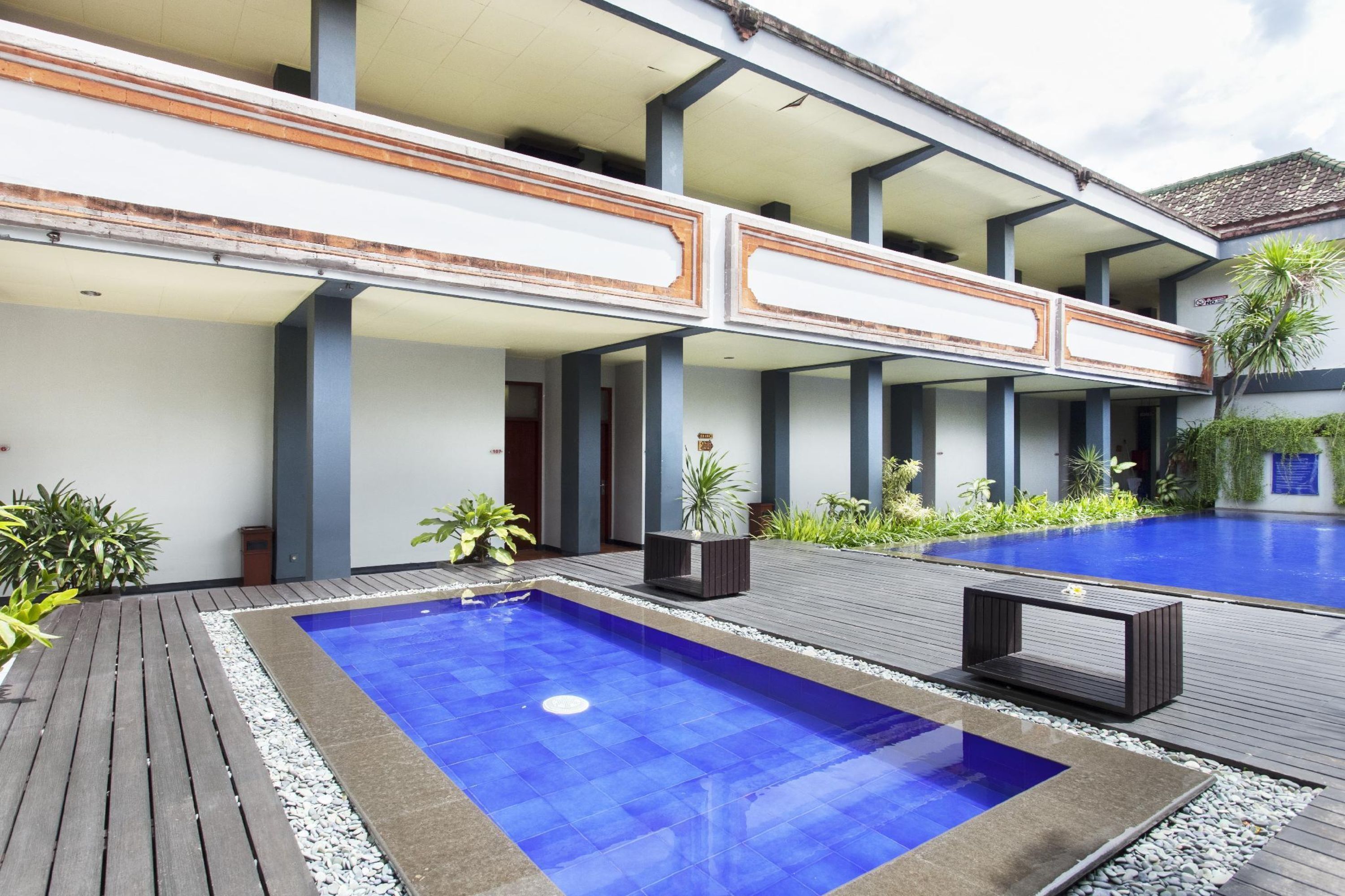 Un hotel moderno con piscina en la azotea, zona de estar al aire libre y un jardín bien cuidado.