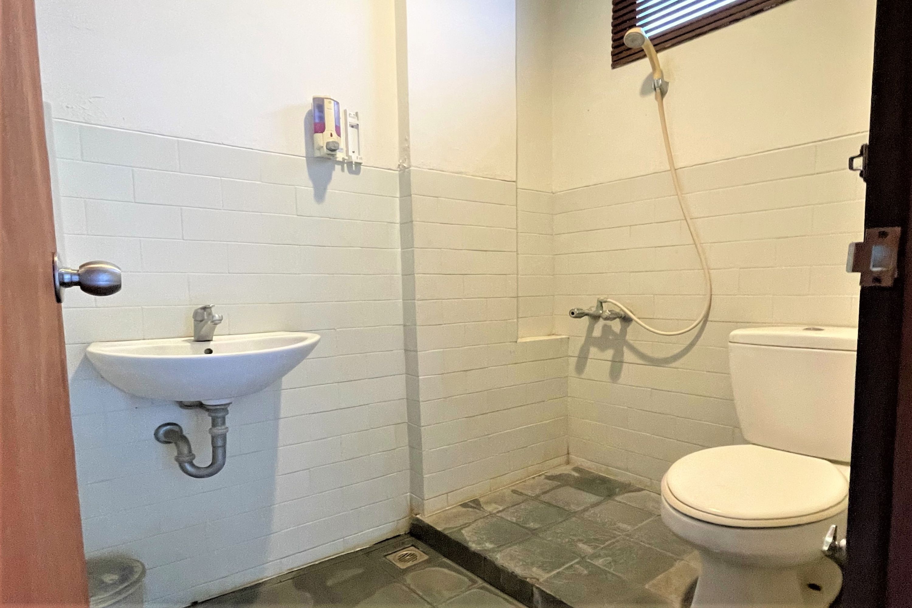 A small bathroom with a white sink, toilet, and shower.