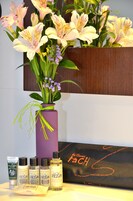 Eine lilafarbene Vase mit Blumen und eine schwarze Schachtel mit Text.