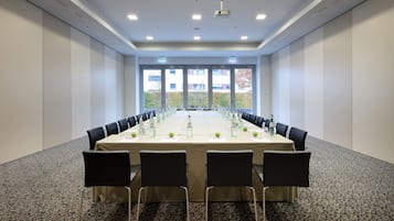 Een vergaderzaal met een lange tafel, stoelen en waterflesjes.