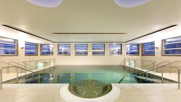 Swimmers can enjoy a refreshing dip in the rectangular pool surrounded by a tiled floor and stairs with metal railings.