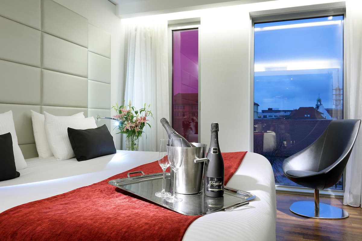 A hotel room with a bed, a tray with champagne, glasses, and a bottle.