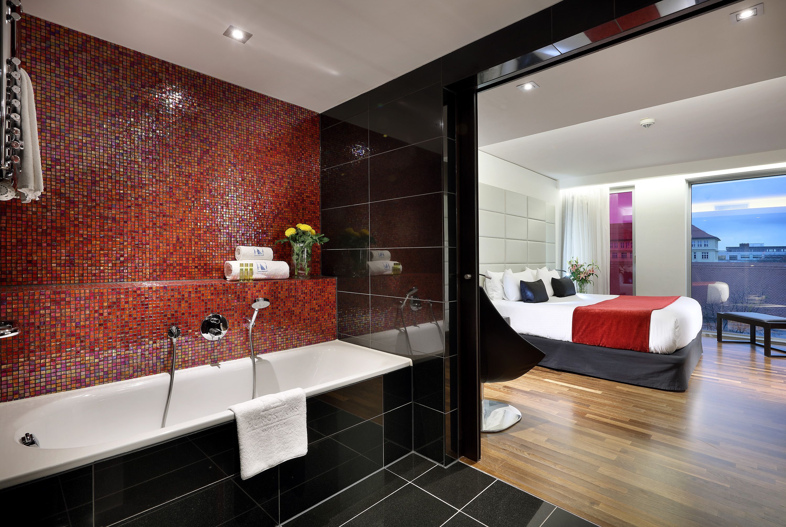 A modern bathroom with a large bathtub, a shower, and a mosaic tile wall.