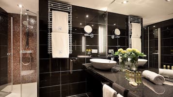 A modern bathroom with a glass-enclosed shower, a large mirror, and a vanity with a bowl sink.