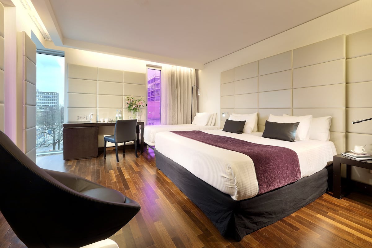 A modern hotel room with a large bed, a desk, and a chair.