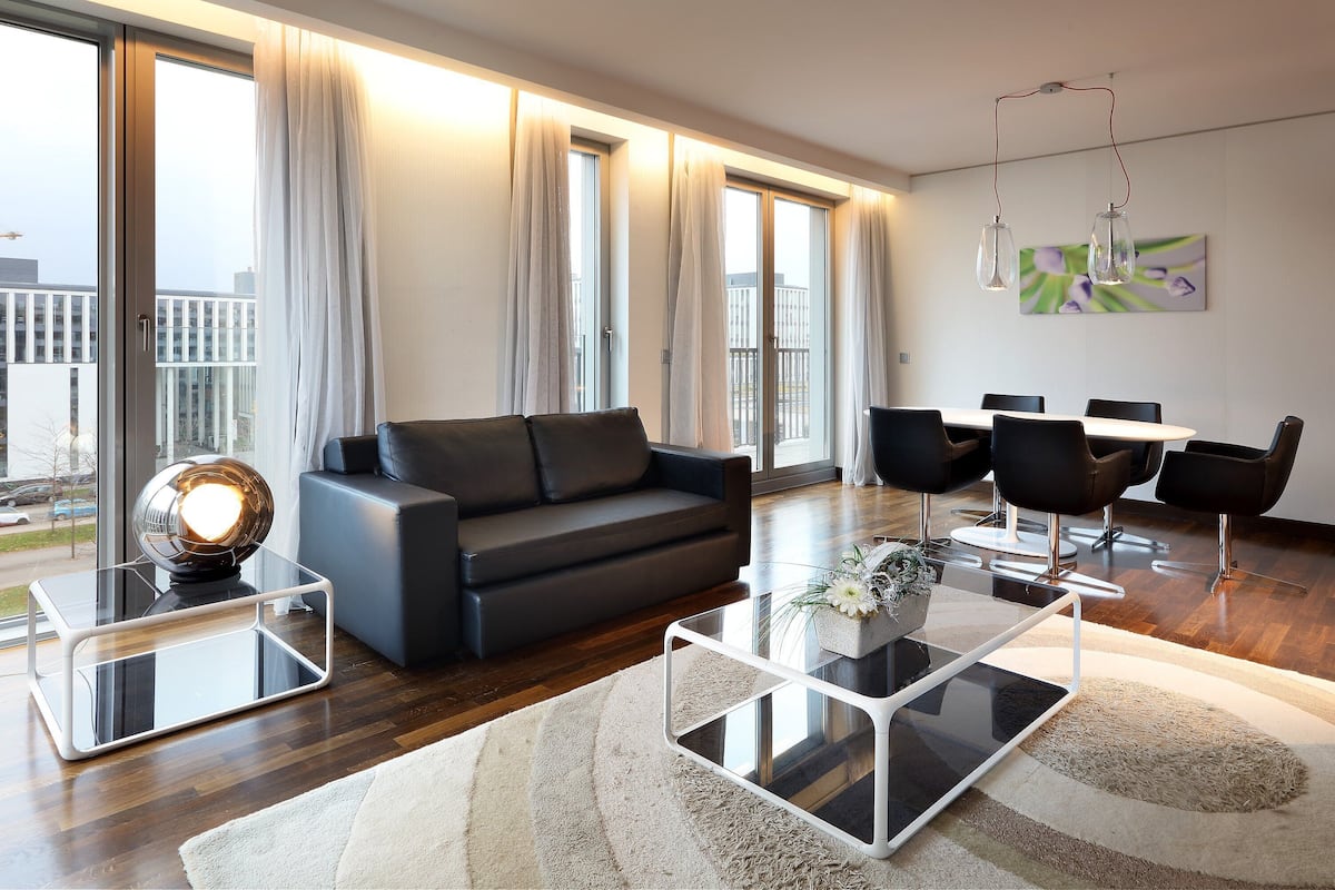 A modern living room with a sofa, coffee table, and dining area.