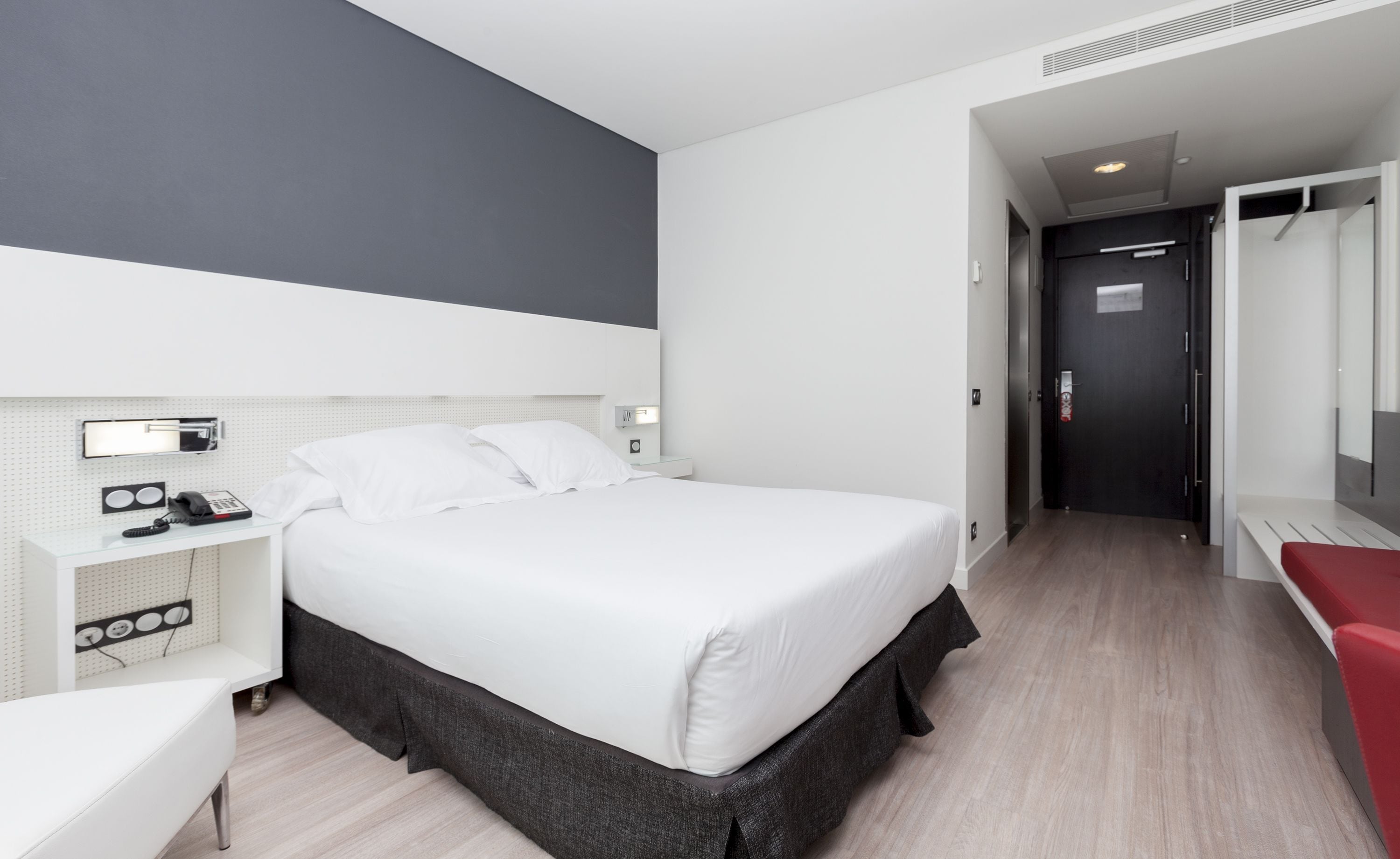 Una habitación de hotel moderna con una cama grande, un escritorio con teléfono y un espejo.
