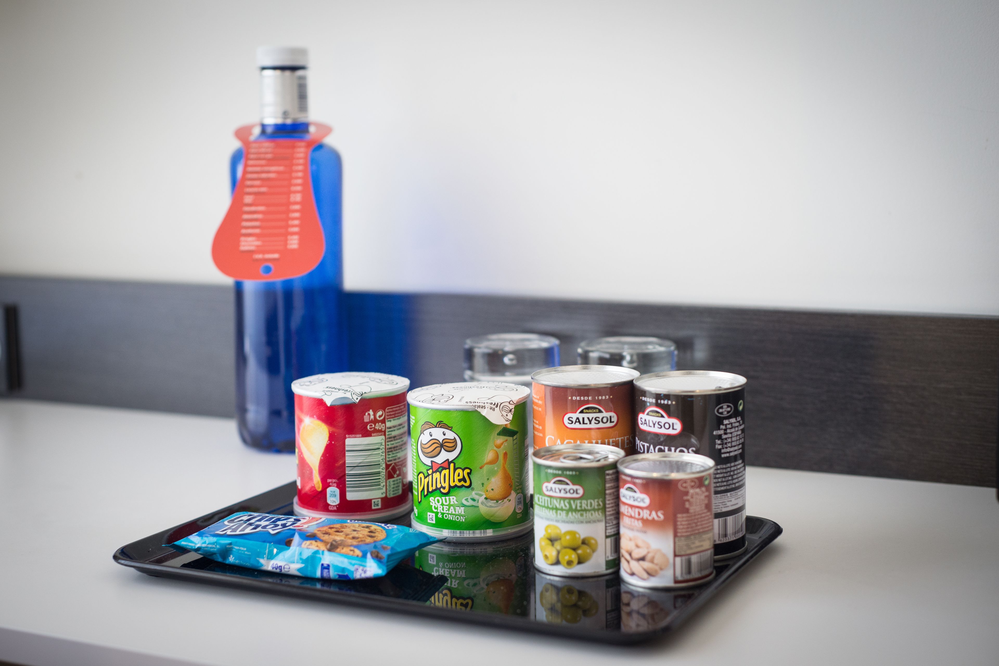 A tray with various food items including Pringles, a bottle of water, and several cans of food.