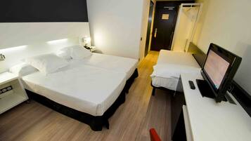 Ein Hotelzimmer mit zwei Betten, einem Schreibtisch mit Computer und einer Duschkabine.