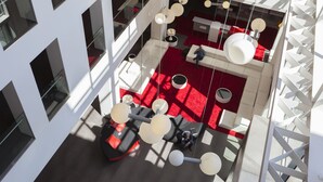 A modern interior with a red carpet, white furniture, and hanging spherical light fixtures.
