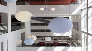 A modern interior with a red carpet, white furniture, and hanging spherical light fixtures.