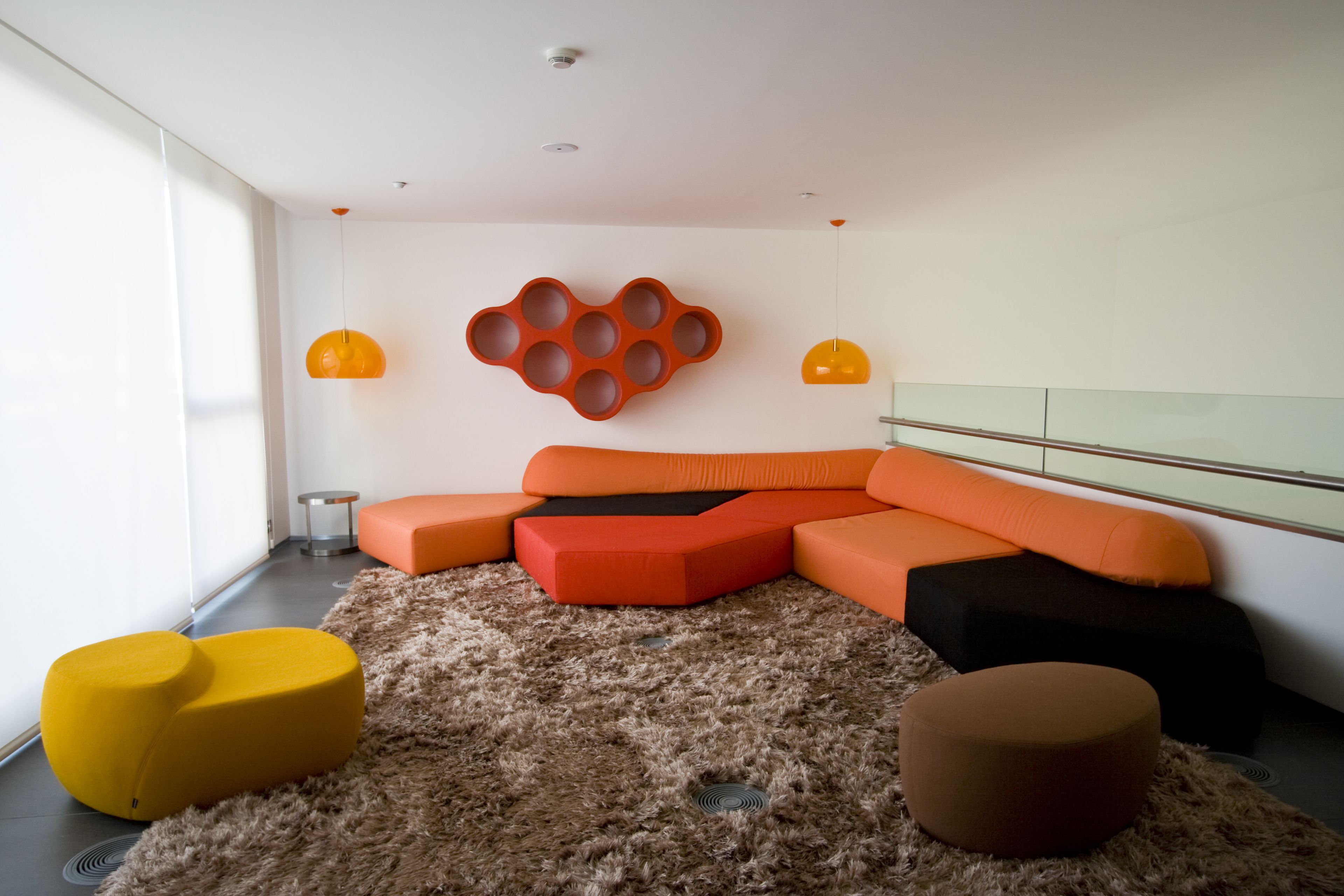 Una sala de estar moderna con un sofá modular, un tapete mullido y dos lámparas colgantes.