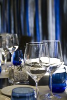 Ein Tisch, gedeckt mit Weingläsern, Tellern und einer blauen Vase.