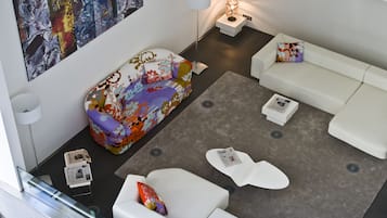 Uma sala de estar moderna com um sofá colorido, sofás brancos e um tapete cinza.