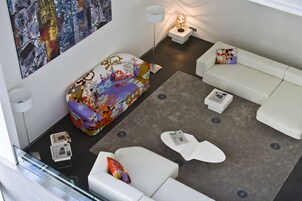 A modern living room with a colorful sofa, white couches, and a grey carpet.