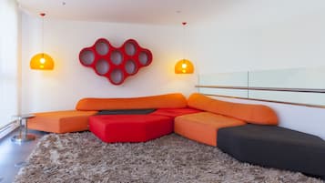 A modern living room with a sectional sofa in red and orange, a fluffy rug, and two pendant lights.