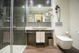 Un bagno moderno con box doccia in vetro, lavabo con specchio e water.