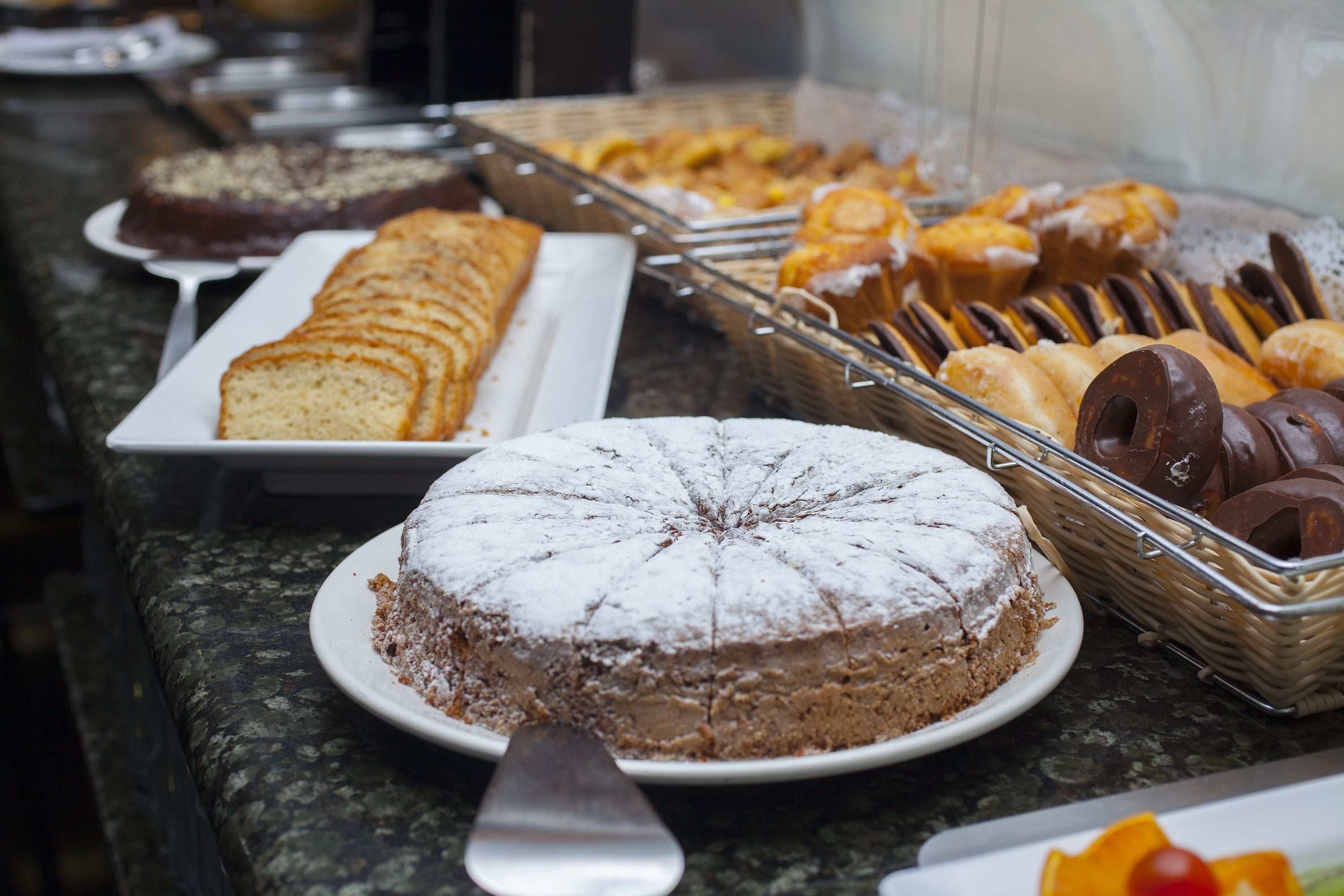 Un buffet proposant une variété de desserts, notamment un gâteau au chocolat, des pâtisseries et du pain.