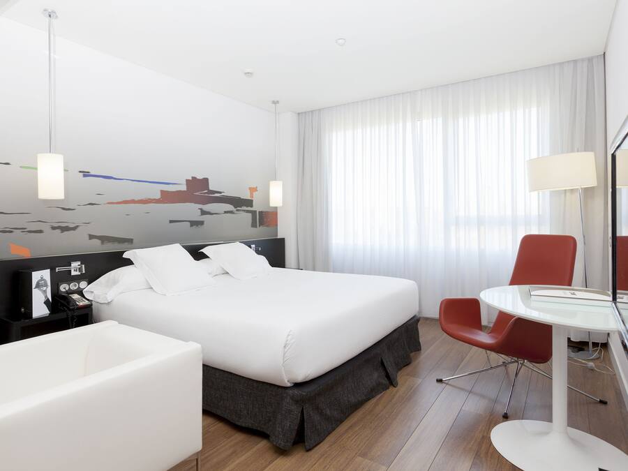 Una habitación de hotel moderna con una cama grande, un escritorio, una silla y un baño.