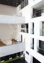 A modern hotel lobby with a high ceiling, a reception desk, and a seating area with a sofa.