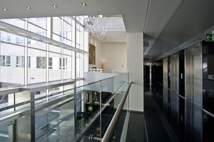Ein modernes Interieur mit Glastrennwand, einer Rezeption und einer Treppe.