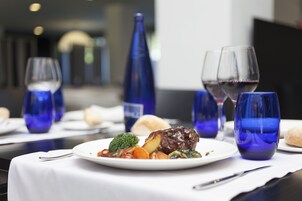Ein Esstisch mit einem Teller Essen, Weingläsern und blauem Glas.