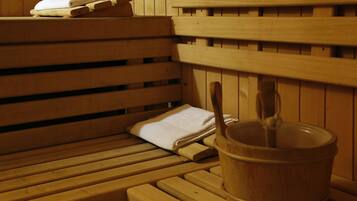 Eine Saunabank aus Holz mit Handtuch und Holzeimer.