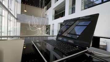 Un interior moderno con una laptop sobre una superficie reflectante, ventanas amplias y un diseño contemporáneo.