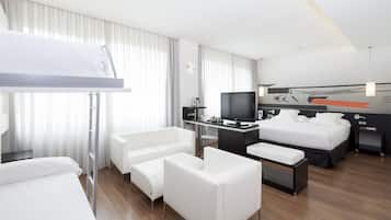 A modern hotel room with a bunk bed, a desk with a computer, a flat-screen TV, a sofa, and a bedside table.