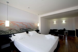 Moderni hotellihuone, jossa on suuri sänky, työpöytä ja tuoli.