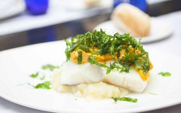 A plate of food with fish, mashed potatoes, and greens.