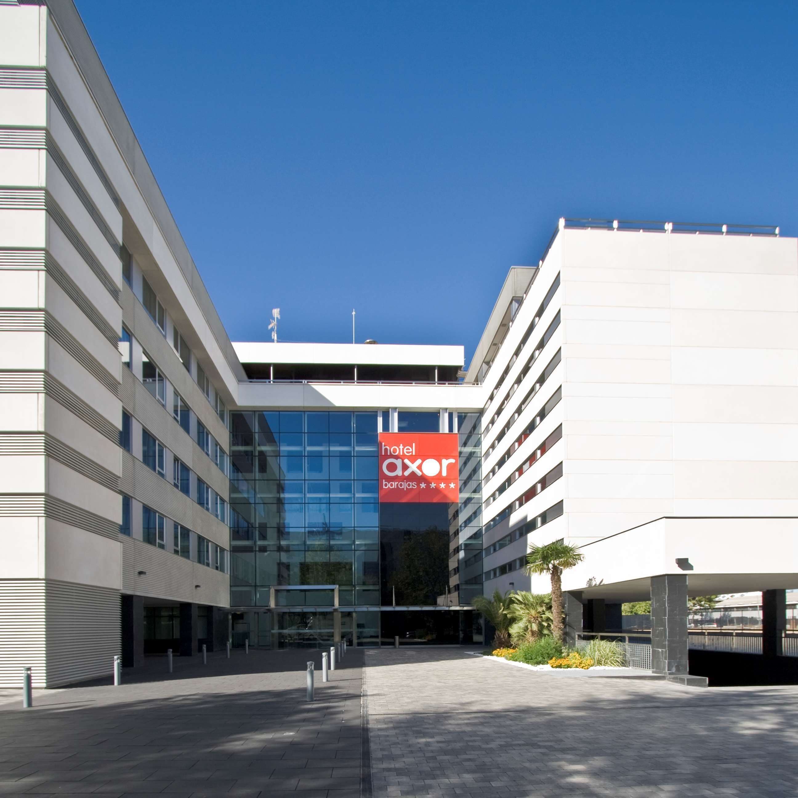 A modern hotel building with a prominent red sign for 'hotel axor'.