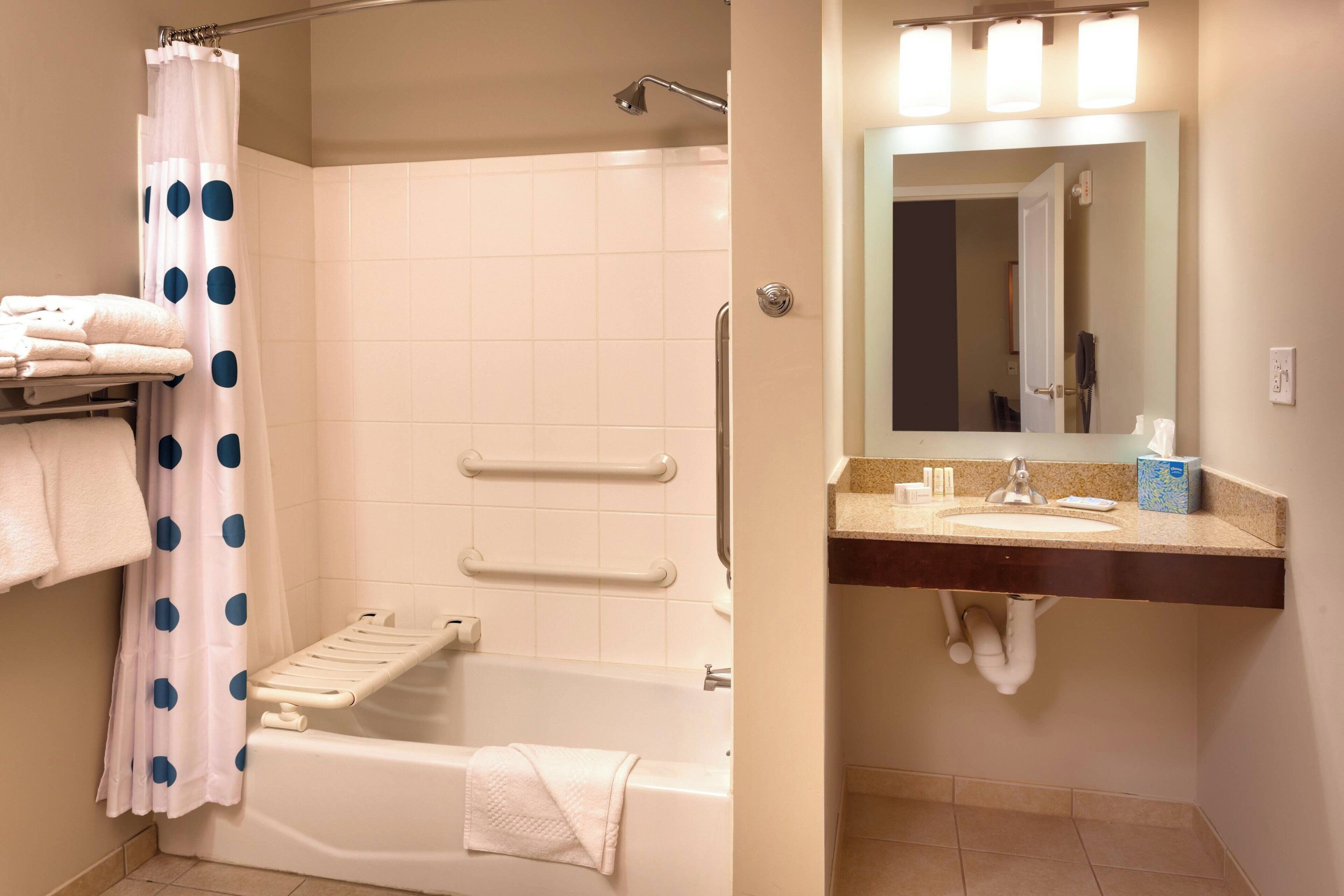 Un baño con bañera, ducha, tocador con espejo y un perchero para toallas.