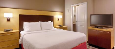 Habitación de hotel con una cama grande, lámparas de noche, televisión, armario y una puerta.