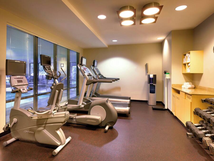 Une salle de sport équipée de tapis de course, de vélos elliptiques et d’haltères.