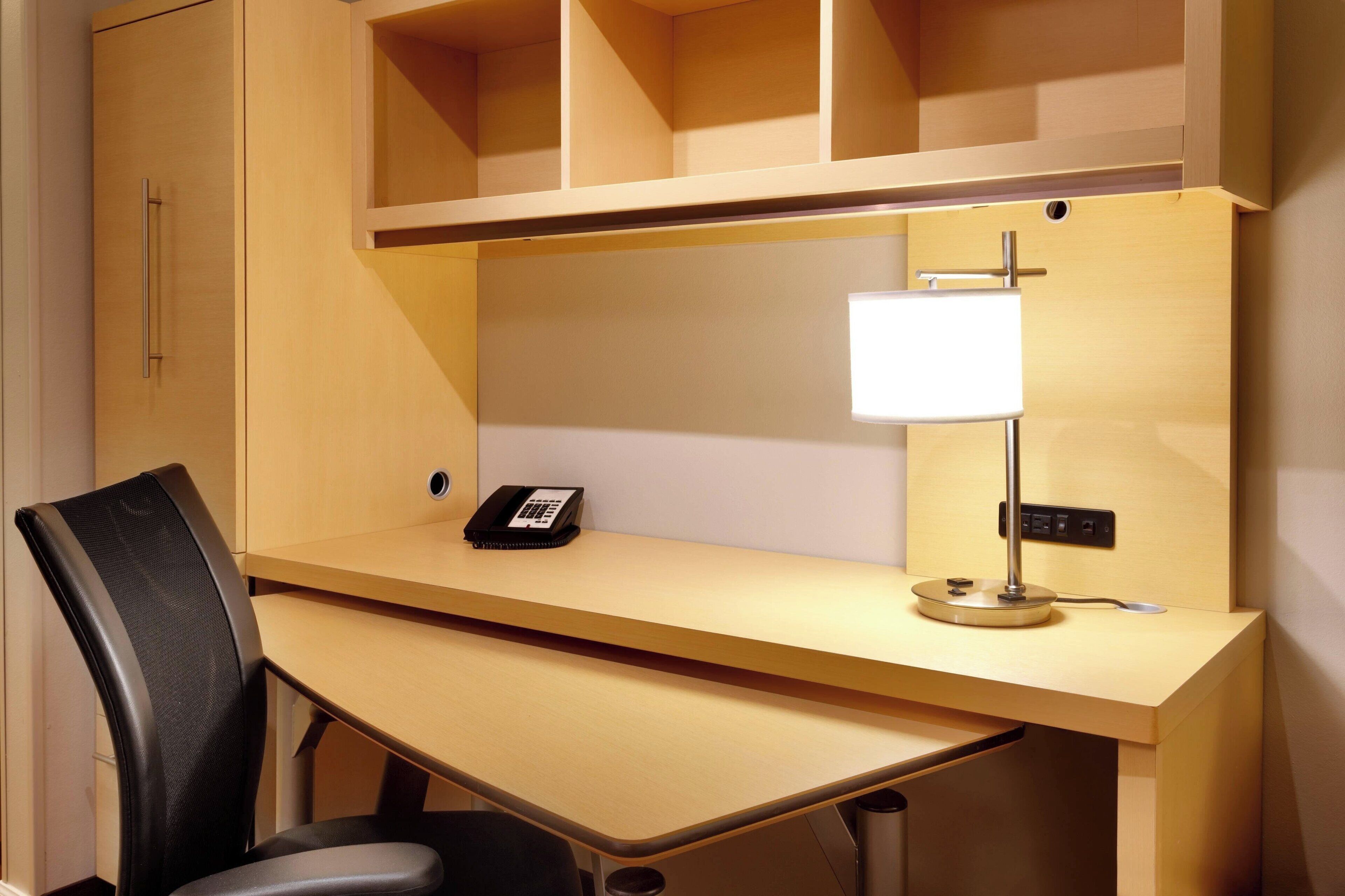 Une chambre d’hôtel équipée d’un bureau, d’une chaise et d’une lampe.