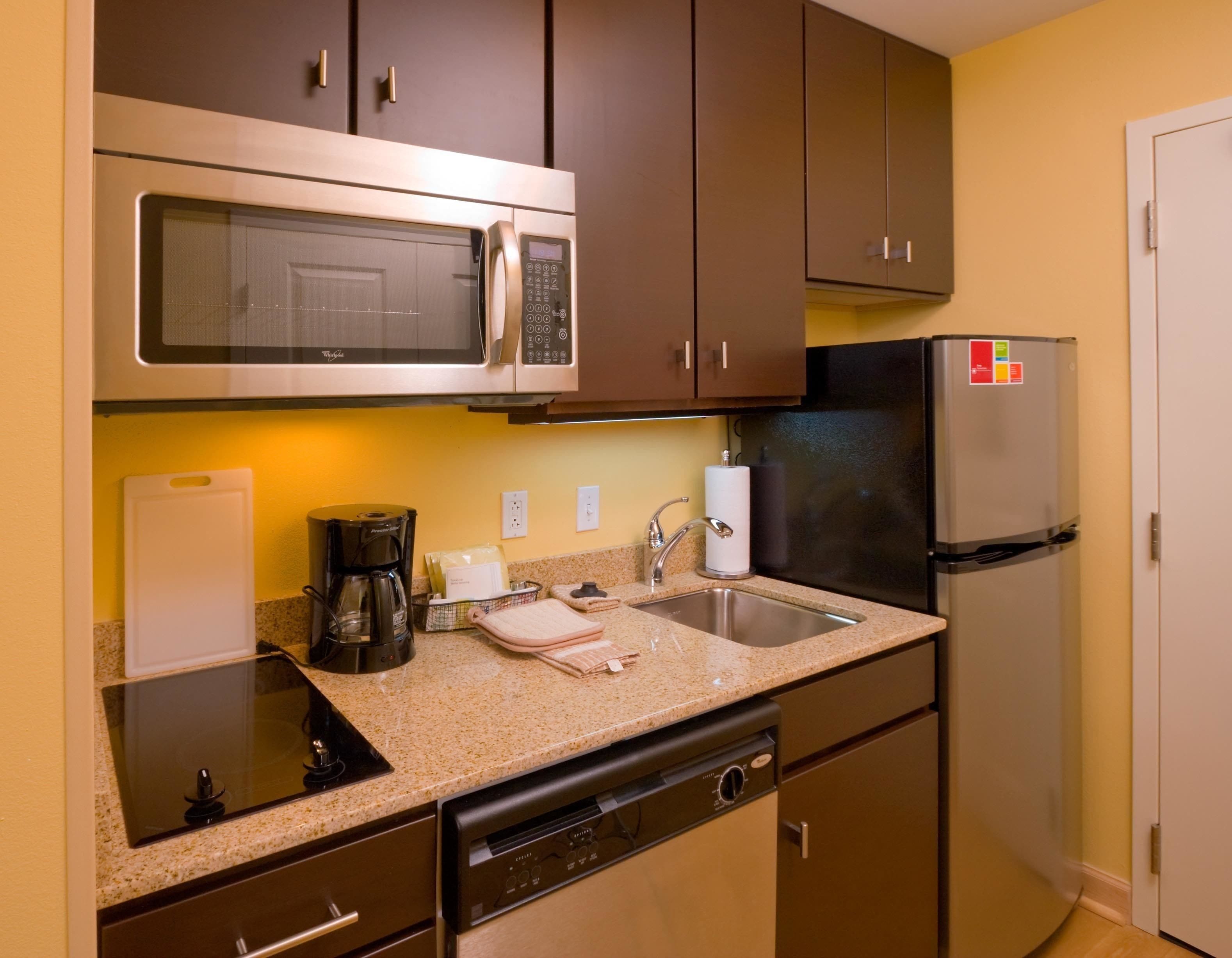 A compact kitchen with a microwave, coffee maker, sink, and dishwasher.