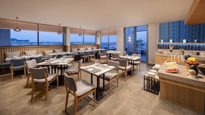 Ein modernes Restaurant mit hohen Decken, großen Fenstern und Blick auf die Stadt.