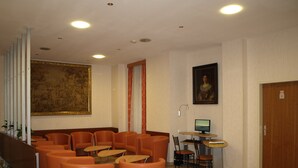 A lobby with orange seating, a large painting, a computer on a desk, and a door with a number sign. - Hotel Terminus Vienna (Vienna)