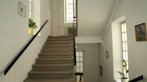 A staircase with a handrail, a radiator, and a window with a plant. - Hotel Terminus Vienna (Vienna)