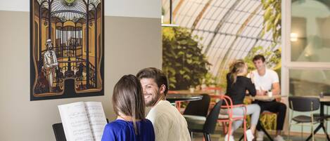 Un piano, une affiche de Bruxelles et un groupe de personnes dans un intérieur moderne.