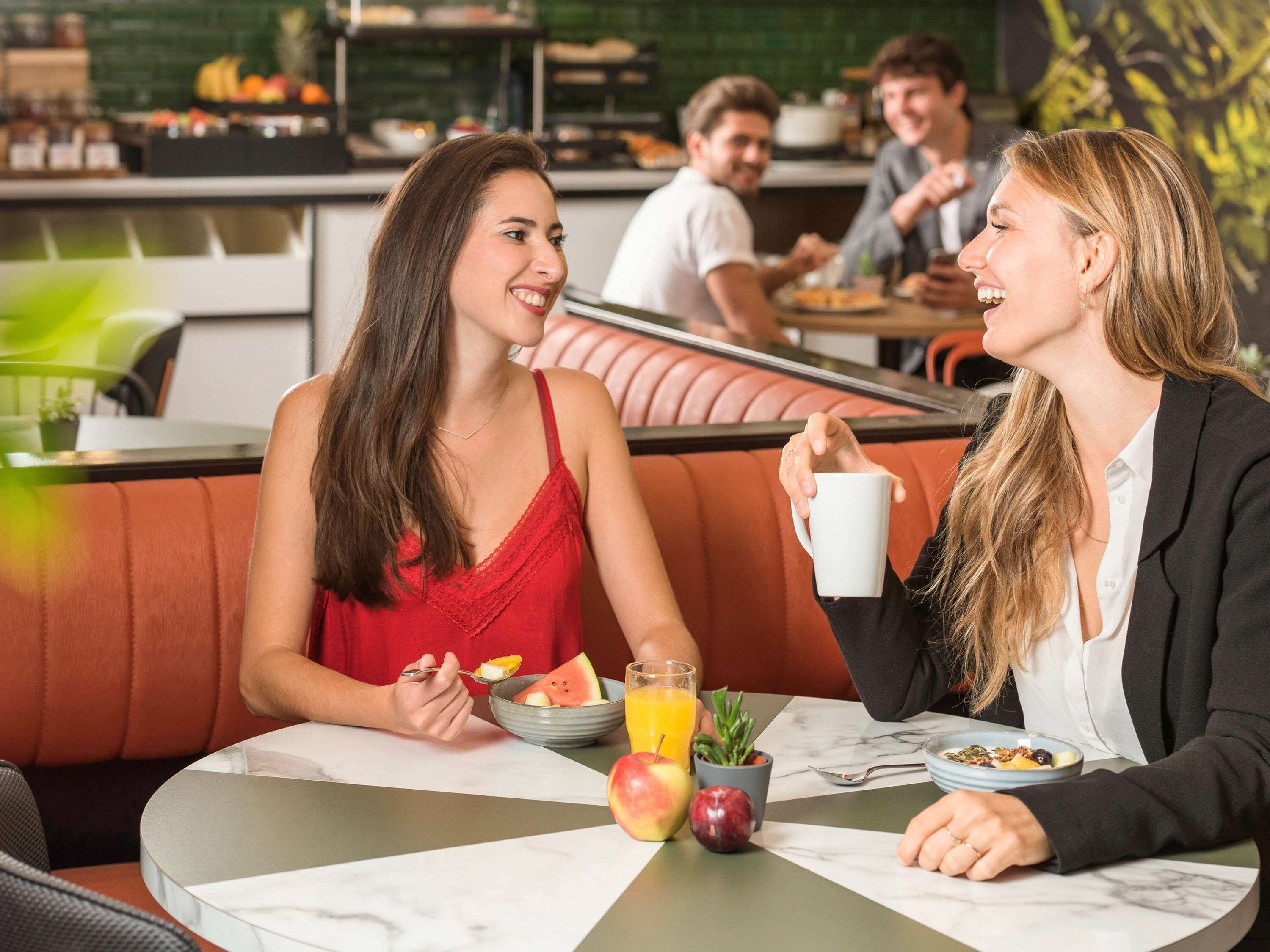 A casual dining area with a booth seating arrangement, a table with breakfast items, and a green wall in the background.
