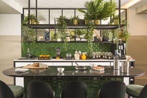 A modern kitchen with a green backsplash, a black countertop, and various kitchen appliances and utensils. - Aparthotel Adagio Brussels Grand Place (Brussels)