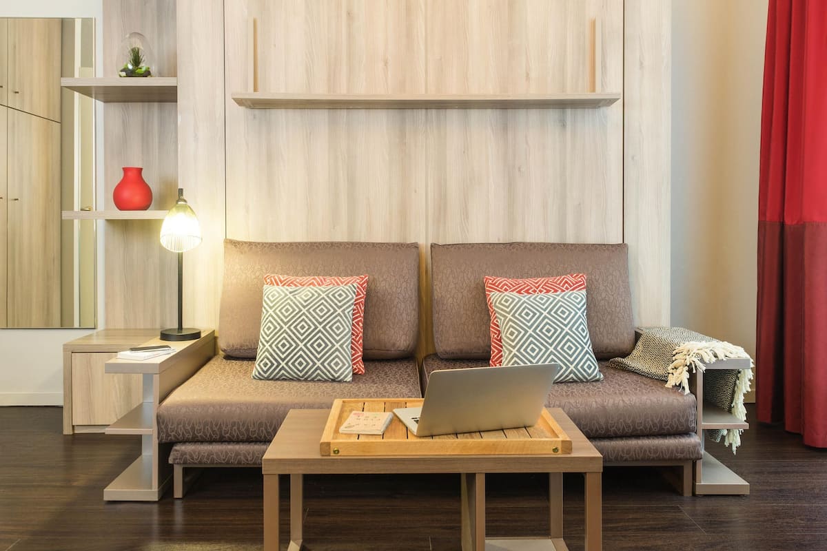 Un salon moderne avec un canapé, une table basse, une lampe et un ordinateur portable.