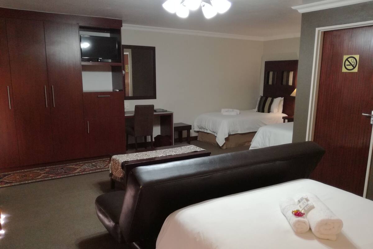 Ein Hotelzimmer mit einem Bett, einem Schreibtisch, einem Sessel, einem Kleiderschrank und einem Fernseher.